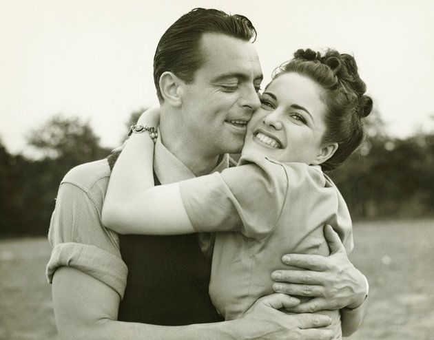 Young couple embracing in field, man kissing woman, (B&amp;W)